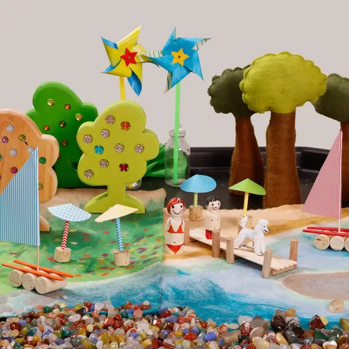 Thementisch zum Thema Sommer mit Spielfiguren, Naturmaterialien und gebastelten Dekorationen