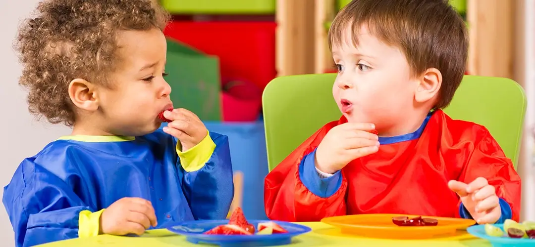 Essende Kleinkinder mit Lätzchen