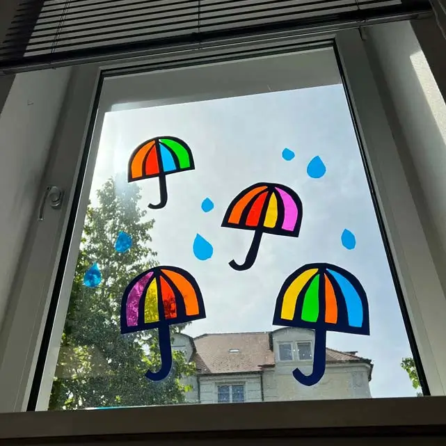 Selbst gebastelte Fensterbilder in der Form von Regenschirmen